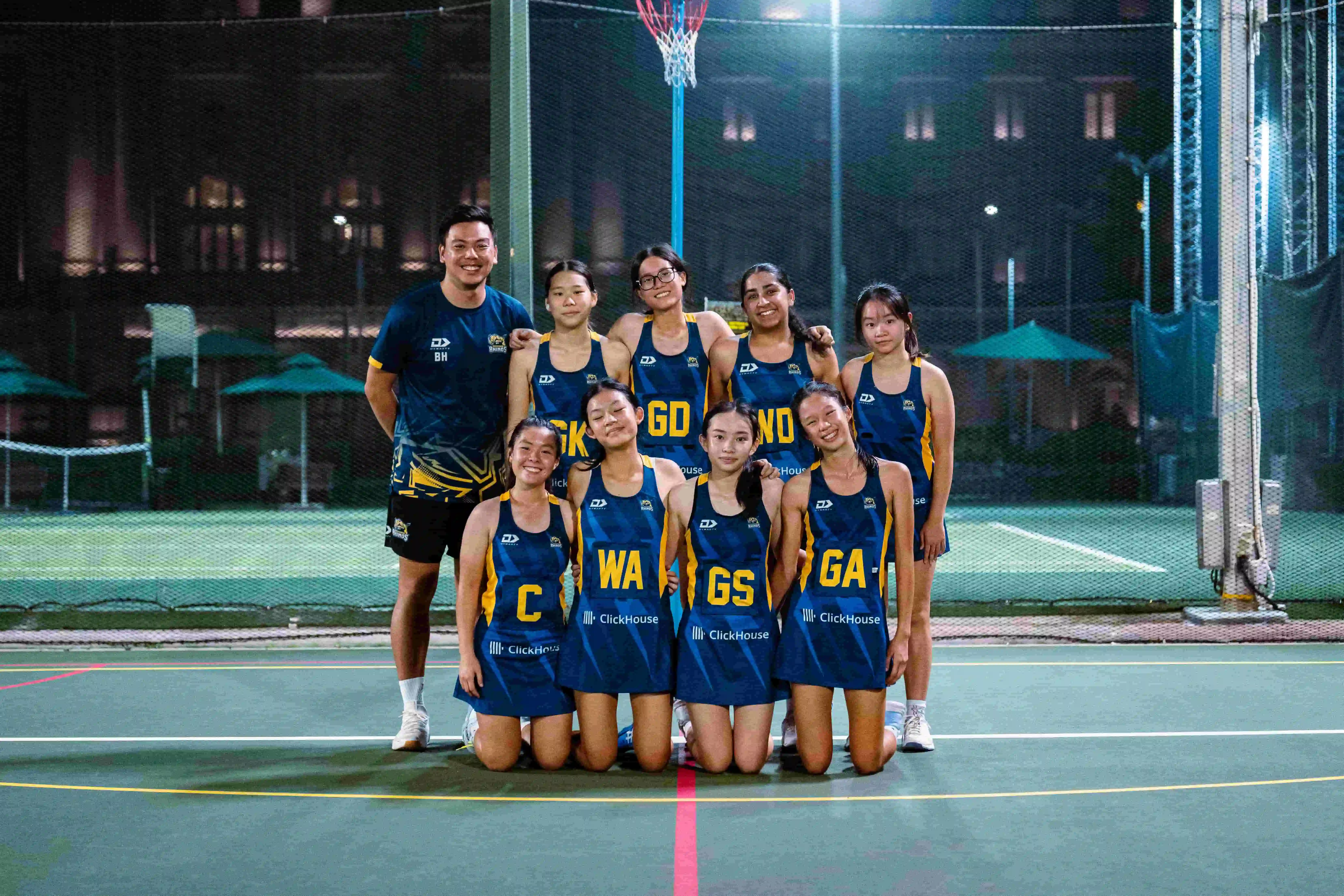 Full team squad and coach portrait on court under floodlights